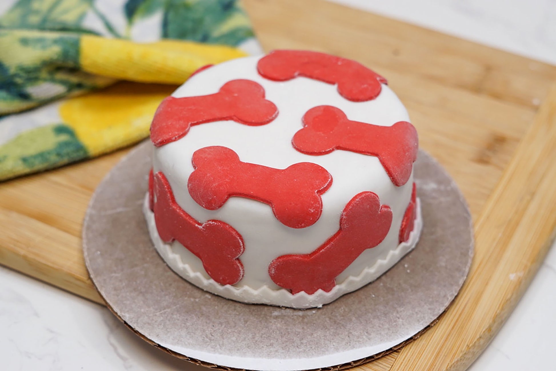 Small round cake with red bone designs on a wooden board
