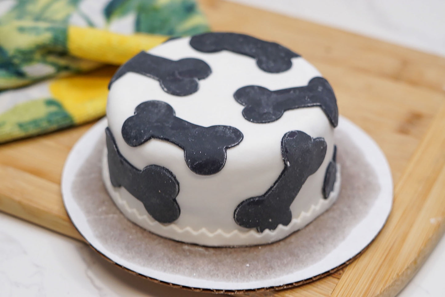 Close-up of a 4-inch dog birthday cake with colored bone decorations and smooth fondant frosting